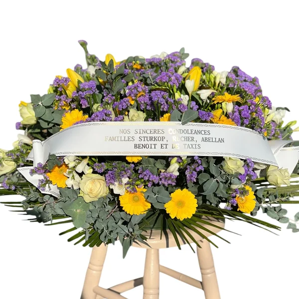 Coussin rond de roses blanches, gerberas jaunes et fleurs violettes